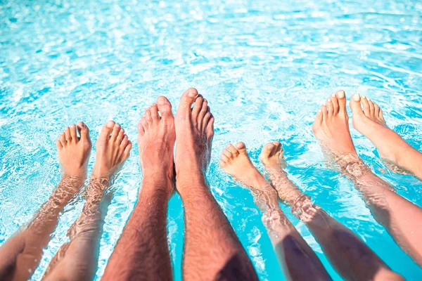 Primo piano di quattro persone gambe a bordo piscina — Foto Stock