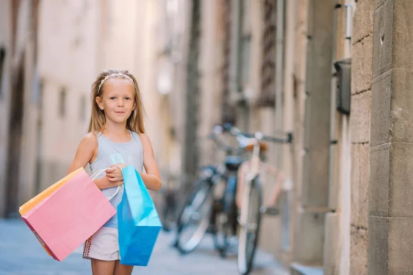 Portrait of adorable little girl walking with shopping bags outdoors in european city. — Stock Photo, Image