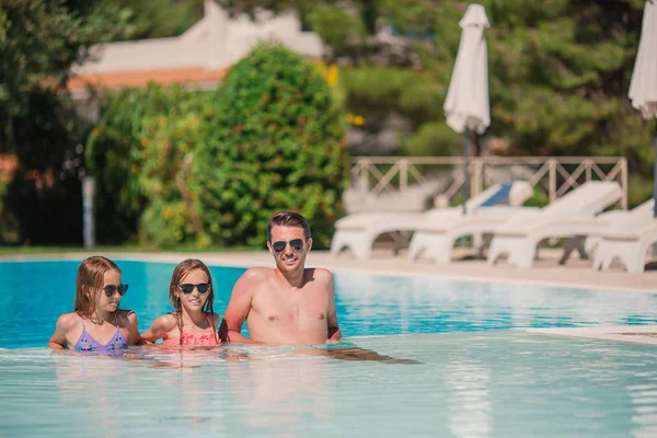 Familia feliz de tres en la piscina al aire libre — Foto de Stock