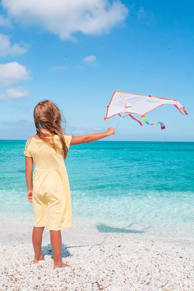 Lite rinnande flicka med flygande drake på tropiska stranden. Kid spela på Ocean Shore. — Stockfoto