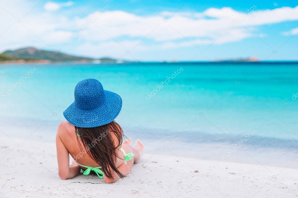 Young woman enjoying the sun sunbathing by perfect turquoise ocean