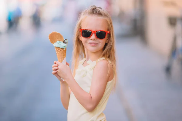 Очаровательная маленькая девочка ест мороженое на открытом воздухе летом . — стоковое фото