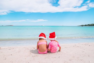 Noel Baba şapkaları beach tatil sırasında küçük sevimli kız birlikte eğlenin