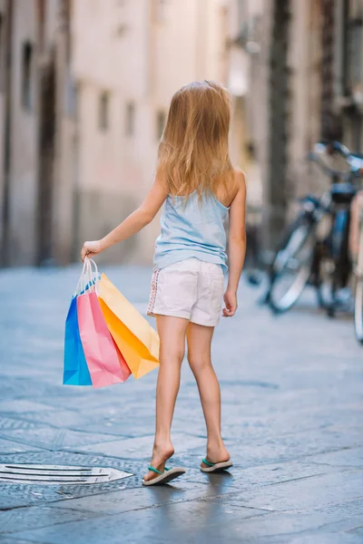 Retrato de niña adorable caminando con bolsas de compras al aire libre en la ciudad europea . — Foto de Stock