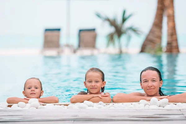 Mother and two kids enjoying summer vacation in luxury swimming pool — Stock Photo, Image
