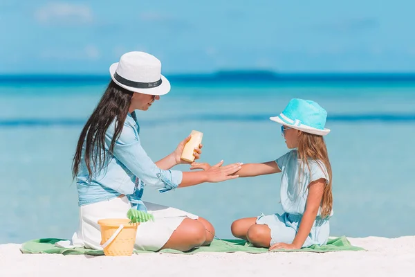 Giovane madre che applica la crema solare al naso figlia sulla spiaggia. Protezione solare — Foto Stock