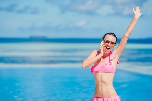 Young beautiful woman talking by phone on white beach — Stock Photo, Image