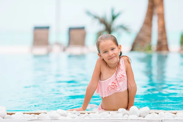 Adorable little girl swimming at outdoor swimming pool — Stock Photo, Image