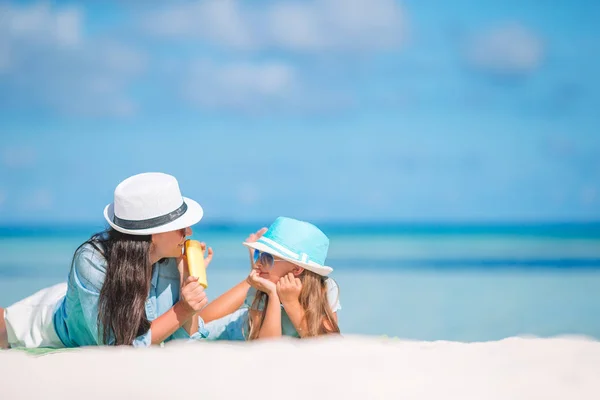 年轻的母亲在海滩上给女儿的鼻子涂防晒霜.防晒 — 图库照片