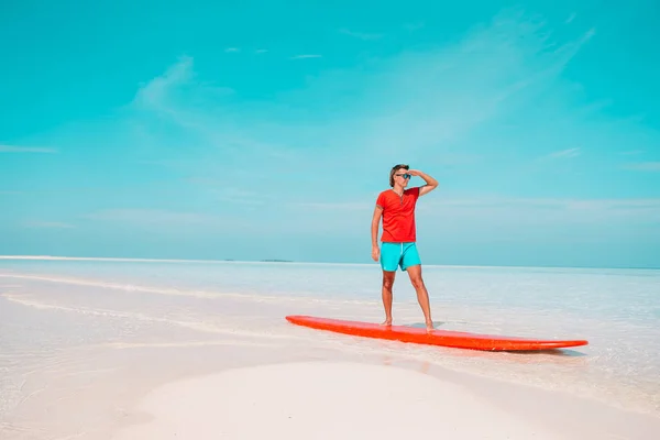 Buon giovane surfista sulla tavola da surf rossa al mare — Foto Stock