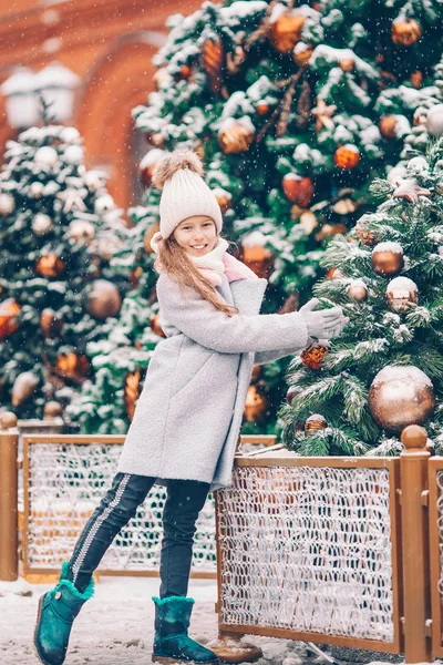 Little happy girl near fir-tree branch in snow for new year. — Stock Photo, Image