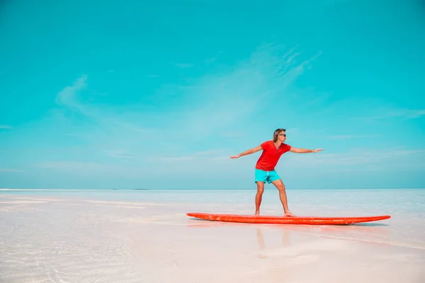 Szczęśliwy młody surfer na czerwonej desce surfingowej nad morzem — Zdjęcie stockowe