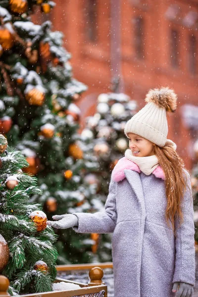 Lille glad pige nær grantræ gren i sne til nytår . - Stock-foto