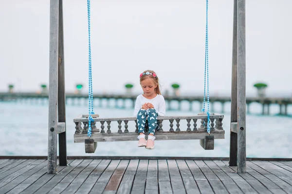 Adorable little girl on swing at sunset — Stock Photo, Image