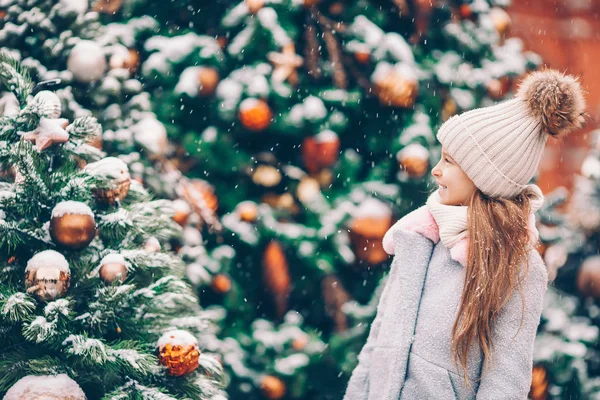 Little happy girl near fir-tree branch in snow for new year. — Stock Photo, Image