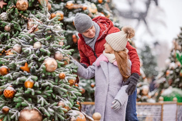 Kleines glückliches Mädchen in der Nähe von Tannenzweig im Schnee für Neujahr. — Stockfoto