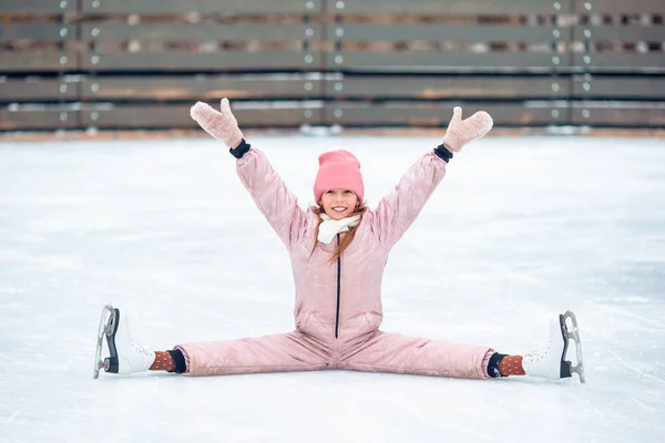 Petite adorable fille assise sur la glace avec des patins après l'automne — Photo