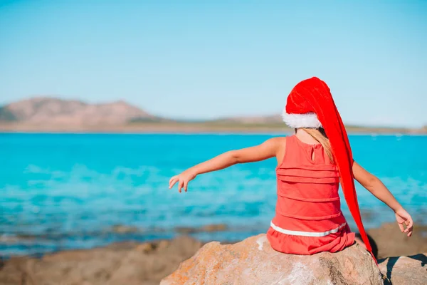 Menina adorável em chapéu de Santa na praia tropical — Fotografia de Stock