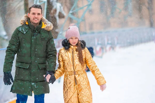 Papá joven y adorable niña se divierten en la pista de patinaje al aire libre — Foto de Stock