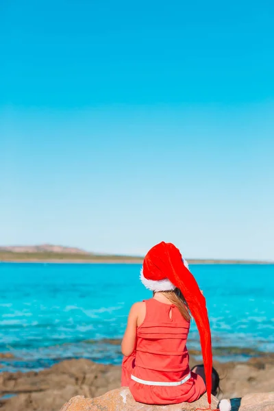 Adorable little girl in Santa hat on tropical beach — Stock Photo, Image