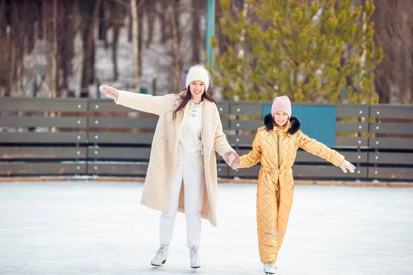Маленька чарівна дівчинка з матір'ю катається на ковзанах на льоду — стокове фото