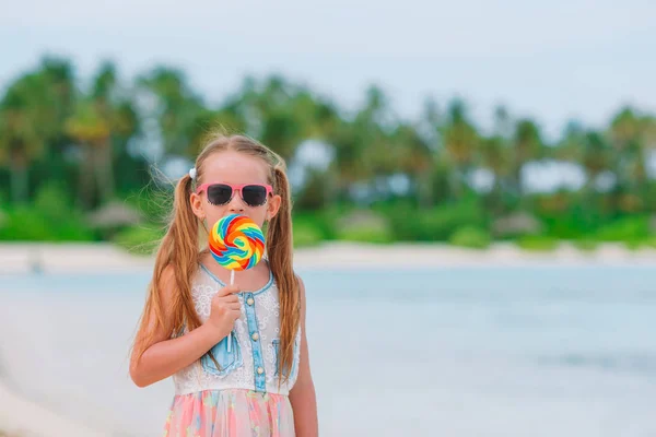Menina adorável com pirulito na praia tropical — Fotografia de Stock