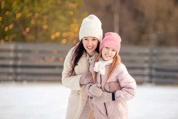 Niña adorable con su madre patinando en pista de hielo —  Fotos de Stock
