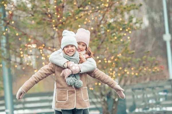 Aranyos lányok korcsolyázás ice rink kint a téli hó nap — Stock Fotó