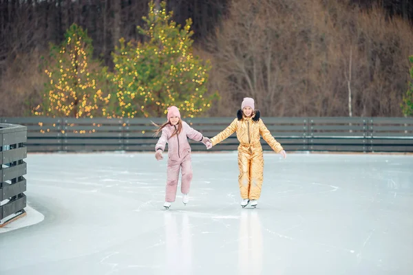 Adorables filles patinant sur la patinoire à l'extérieur en hiver journée de neige — Photo