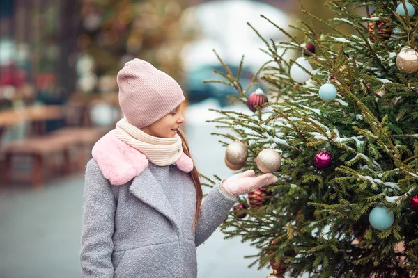 Gelukkig meisje in de buurt van fir-tree branch in sneeuw voor Nieuwjaar. — Stockfoto