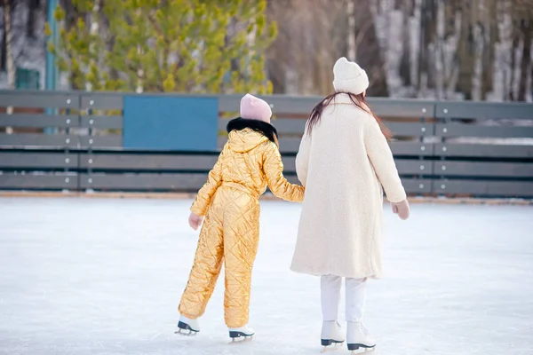 Маленька чарівна дівчинка з матір'ю катається на ковзанах на льоду — стокове фото