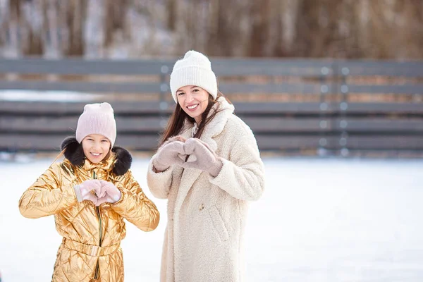 Niña adorable con su madre patinando en pista de hielo —  Fotos de Stock