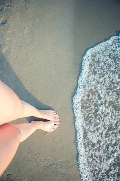 Womens beautiful smooth legs on white sand beach — Stock Photo, Image