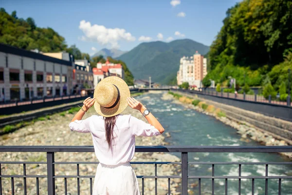 Bonne fille au chapeau sur le remblai d'une rivière de montagne dans une ville européenne . — Photo