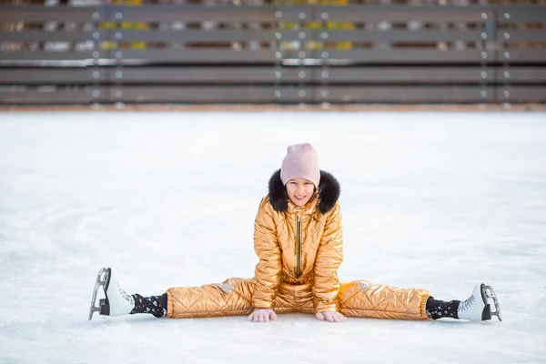 Маленькая очаровательная девочка сидит на льду с коньками после падения — стоковое фото