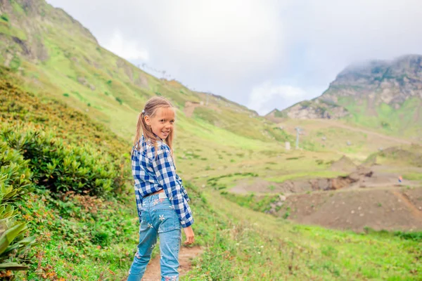 Beautiful happy little girl in mountains in the background of fog — Stock Photo, Image