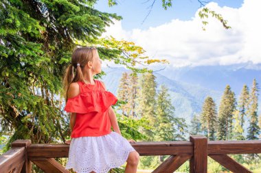 Sisin arkasındaki dağlarda güzel mutlu küçük bir kız.