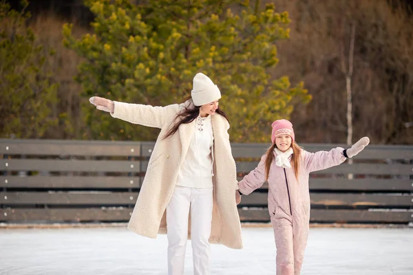Kleines entzückendes Mädchen mit ihrer Mutter beim Schlittschuhlaufen auf der Eisbahn lizenzfreie Stockfotos