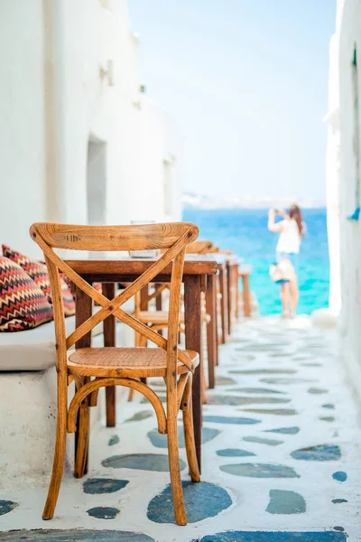 Bancos con almohadas en un típico café al aire libre griego en Mykonos con increíbles vistas al mar en las islas Cícladas —  Fotos de Stock