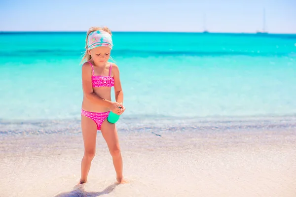 Bambina con bottiglia di crema solare seduta sul bordo della piscina — Foto Stock