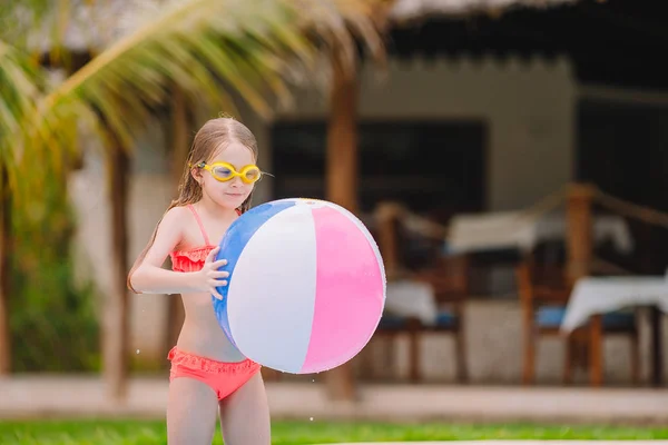 可爱的小女孩微笑着玩充气玩具球在室外游泳池 — 图库照片