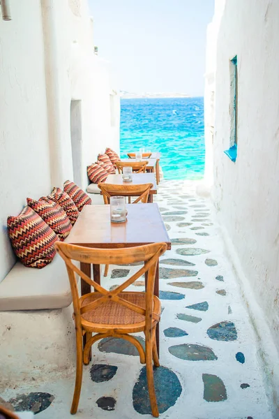 Bancos con almohadas en un típico café al aire libre griego en Mykonos con increíbles vistas al mar en las islas Cícladas —  Fotos de Stock