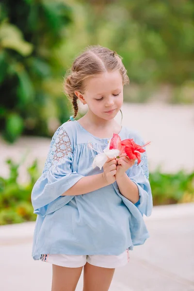 Küçük sevimli kız yaz günü renkli çiçekler kokluyor. — Stok fotoğraf