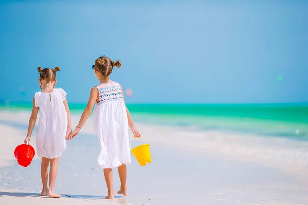 Маленькі щасливі смішні дівчата веселяться на тропічному пляжі, граючи разом. Сонячний день з дощем у морі — стокове фото