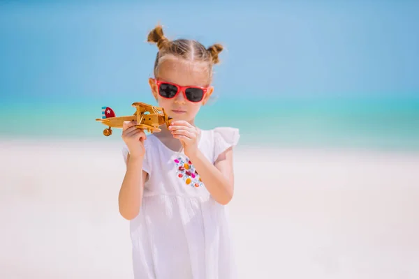 Niña feliz jugando con el avión de juguete en la playa. Sueño de niño de convertirse en piloto — Foto de Stock