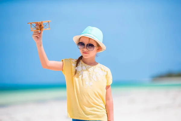 Niña feliz jugando con el avión de juguete en la playa. Sueño de niño de convertirse en piloto —  Fotos de Stock