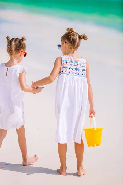Piccole ragazze divertenti felici si divertono molto alla spiaggia tropicale a giocare insieme. Giorno soleggiato con pioggia nel mare — Foto Stock