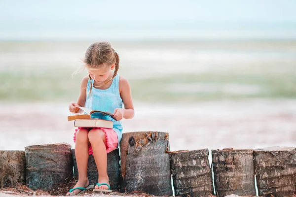 Little adorable girl reading book during tropical white beach — Stock Photo, Image