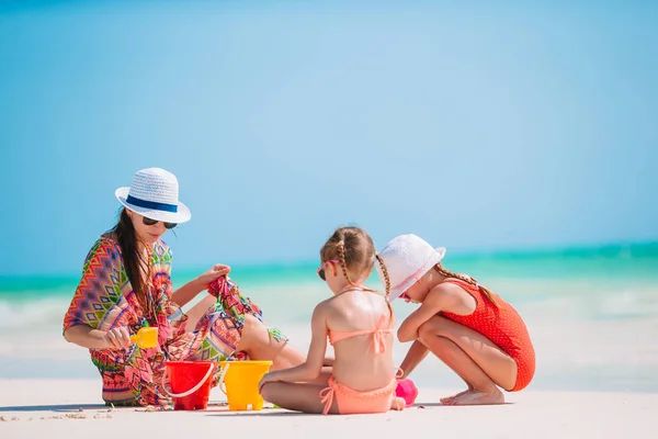 Matka i małe córeczki robiące zamek z piasku na tropikalnej plaży — Zdjęcie stockowe