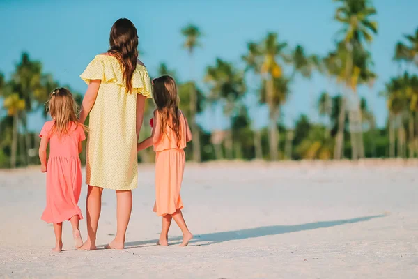 Sevimli küçük kızlar ve beyaz sahilde genç bir anne. — Stok fotoğraf